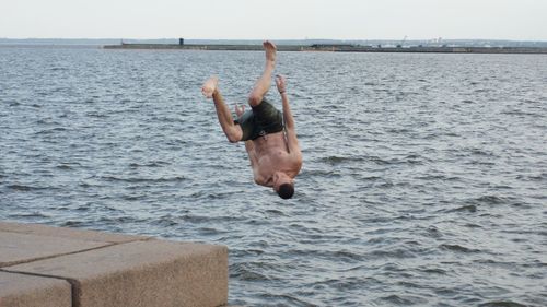 Full length of shirtless man jumping in sea