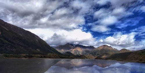 Mountains reflecting on calm lake against cloudy sky