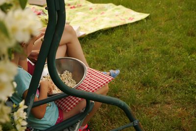 Girl having popcorn while siting on bench in yard