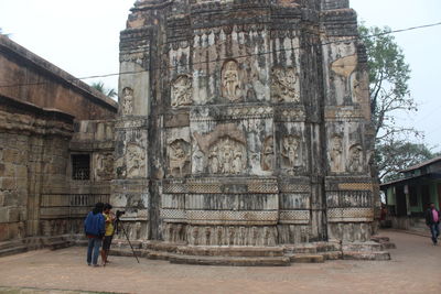 Rear view of man outside temple against building