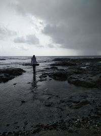 Rear view of man standing on beach against sky
