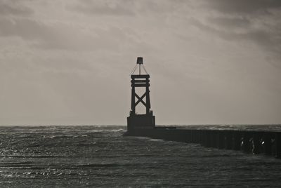 Lighthouse by sea against sky