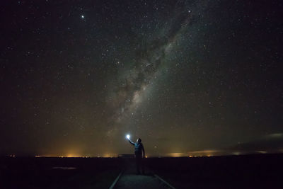 Man holding light while standing against star field