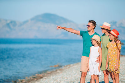 Man pointing away while standing on beach with family