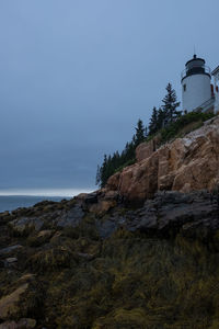 Lighthouse by sea against sky