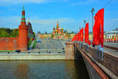 Bridge over river by buildings against sky