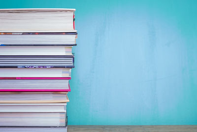 Stack of books on table against blue wall