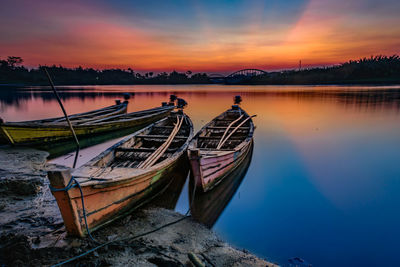 Boat moored in sea against sky during sunset