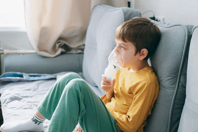 Little boy sits with an inhalation mask during cough and bronchitis. 