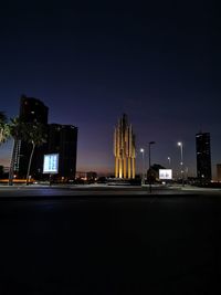 Illuminated city buildings against sky at night