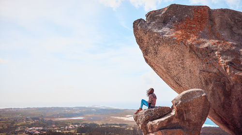 Man looking at rock formation against sky