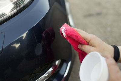 Cropped hand of man washing car