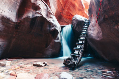 Long exposure of waterfall flowing over rock step in slot canyon