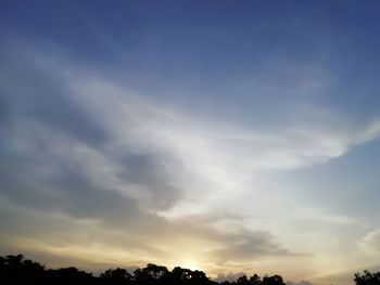 Low angle view of sunlight streaming through clouds