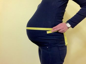 Side view of a pregnant woman measuring tummy