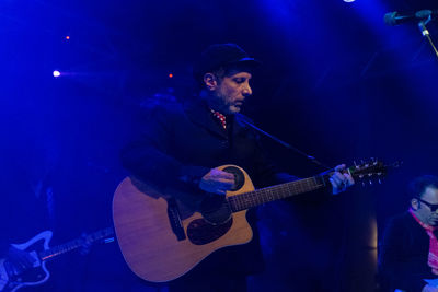 Young man playing guitar at music concert