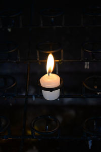 Illuminated candle on stand in darkroom