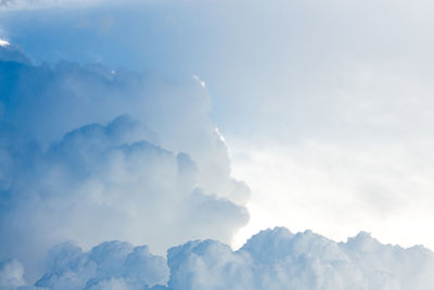 Low angle view of sunlight streaming through clouds