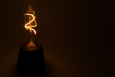 Close-up of illuminated light bulb against black background