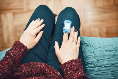 Woman measuring the degree of oxygen saturation of the blood at home using pulse oximeter