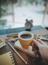 Cropped image of hand holding coffee cup on table