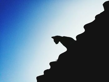 Low angle view of silhouette statue against clear blue sky