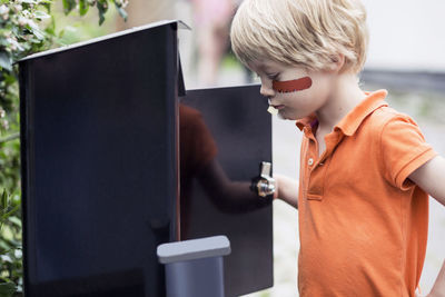 Boy looking into letter box outdoors