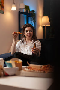 Portrait of young woman sitting on table at home