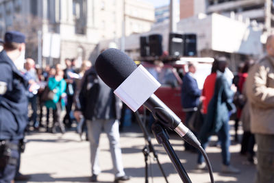 Close-up of microphone with people in background on street