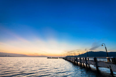 Pier over sea against blue sky during sunset