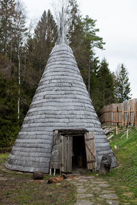 Conical light wooden medieval building with fireplace in the middle.