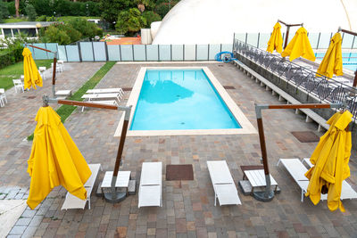 High angle view of lounge chairs by swimming pool