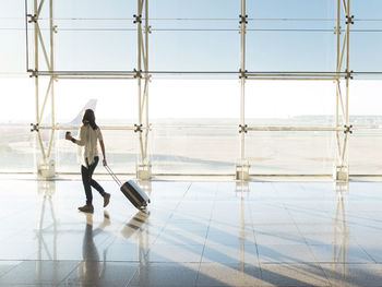 Woman walking with suitcase at the departure hall of the airport.