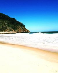 Scenic view of beach against clear blue sky