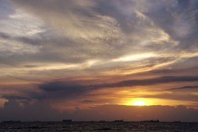 Scenic view of sea against cloudy sky during sunset