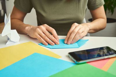 Origami lessons. woman make origami easter rabbit from color paper. diy concept