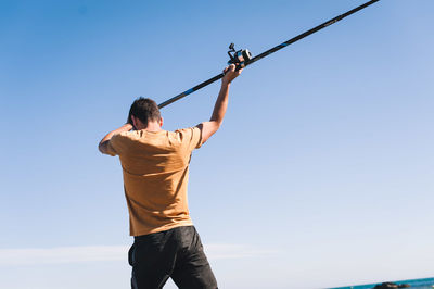 Rear view of man standing against blue sky