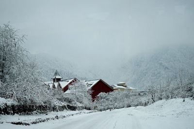 Scenic view of snow covered field by houses against sky