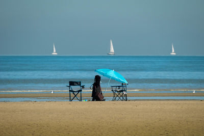 Umbrella and chairs sitting at the waterline of a sandy beach on a sunny day