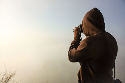 Midsection of man photographing against sky