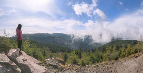 Young woman looking at mountain against cloudy sky