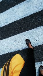 Low section of man standing on zebra crossing