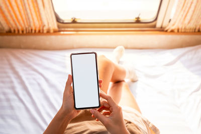 Midsection of man using mobile phone on bed