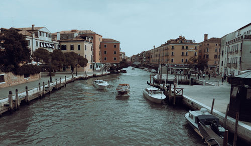 Canal amidst buildings in city against sky