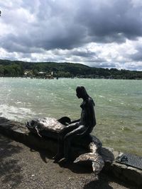 Statue on boat in lake against sky