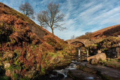 A waterfall and packhorse stone bridge at three shires head in the peak district national park.
