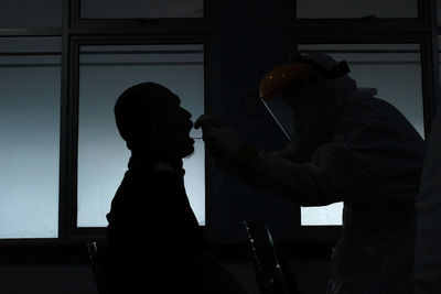 Side view of silhouette man holding window in the dark