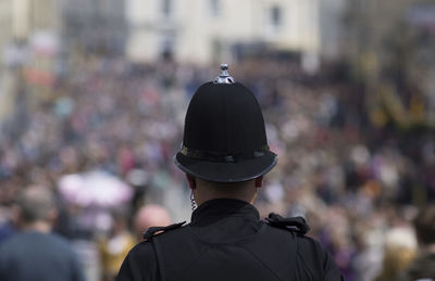 Rear view of police man standing against crowd