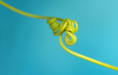 Close-up of yellow wire over blue background