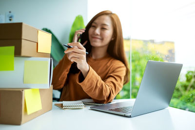 Young businesswoman using laptop while sitting on table